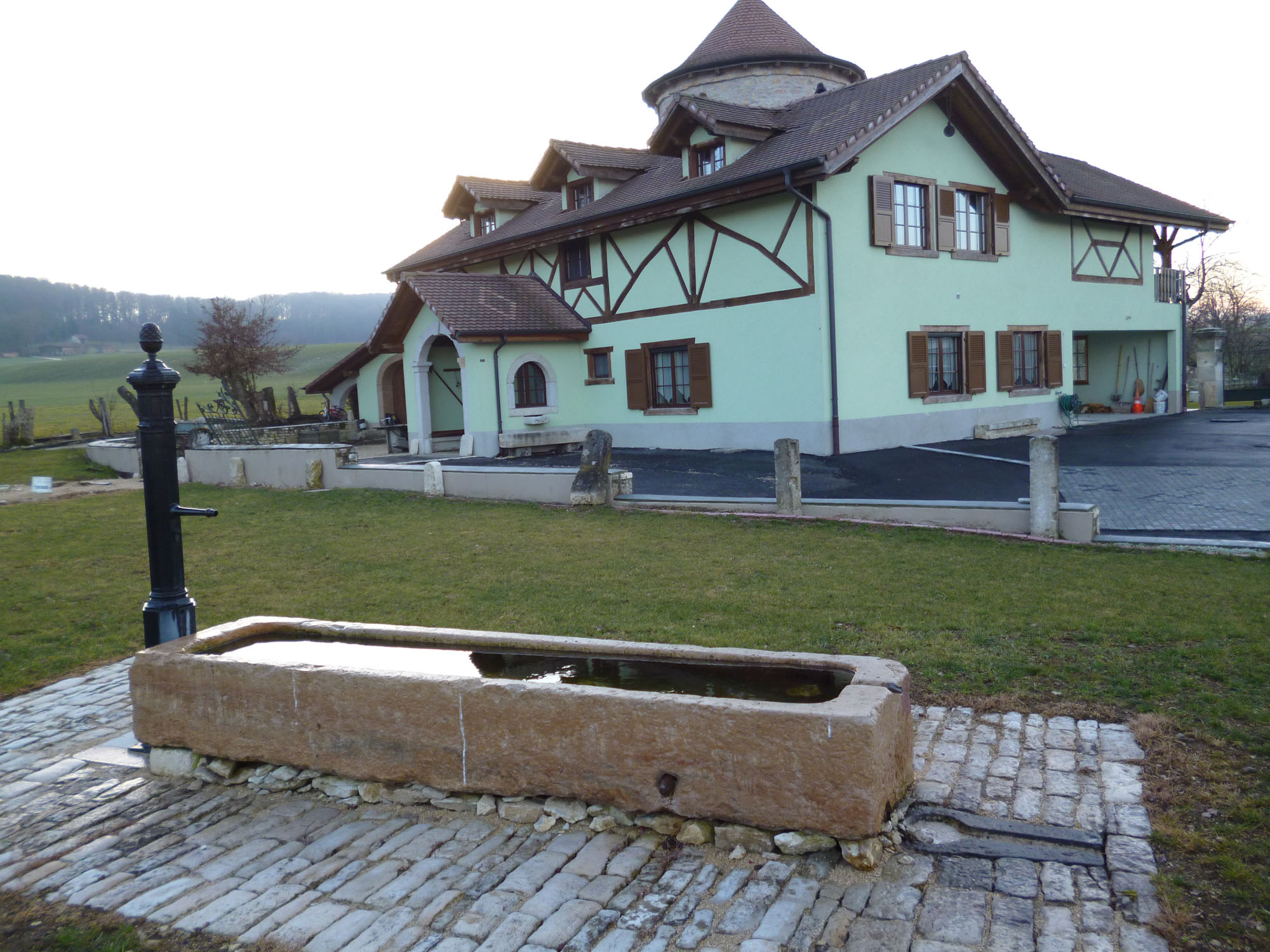 Photo d'une belle maison avec petit toit, toure, voute, colombage, muret, fontaine, gazon